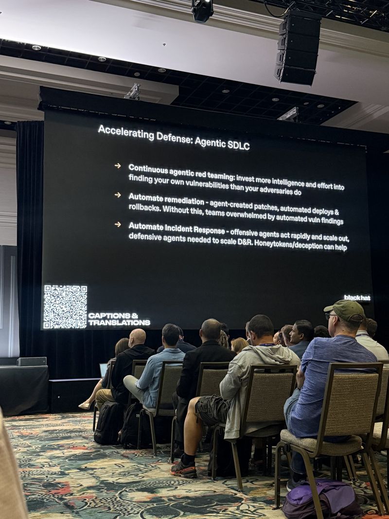Slide: Accelerating Defense Agentic SDLC shown from the back of the room, with the three recommendations on continuous red teaming, automated remediation and automated incident response